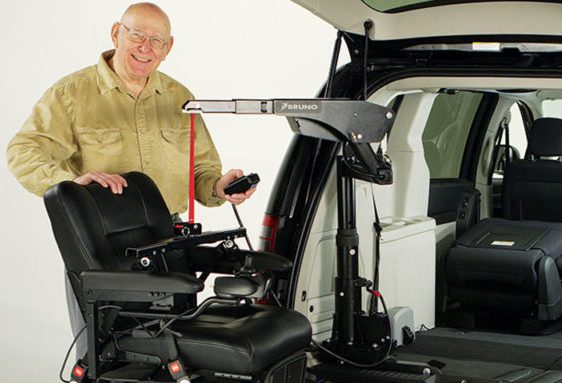 Man loading his wheel charir on a Hoist Vehicle Lift