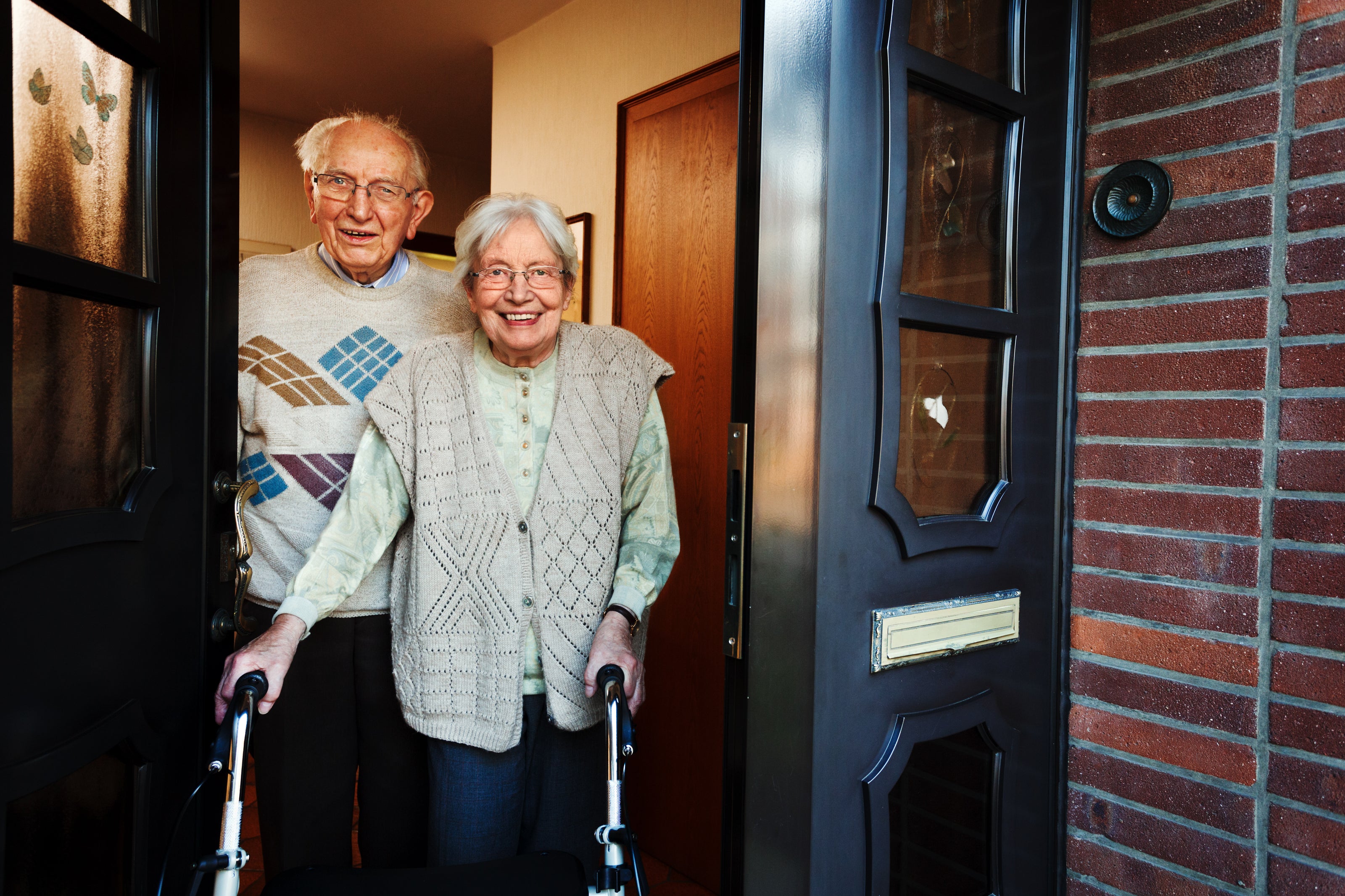 two seniors standing in a handicap accesible home doorway with walkling aids